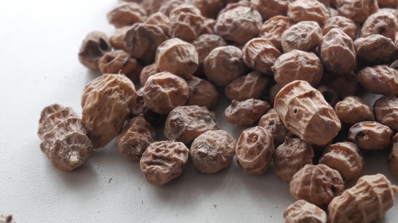 Zigoli dolci essiccati per horchata, ingrediente alimentare sano e rustico su superficie bianca