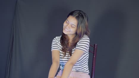 Young-asian-woman-model-sitting-on-chair-and-smiling-at-the-camera-in-studio