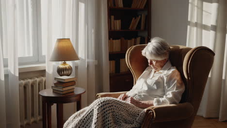 elderly woman relaxing in armchair at home
