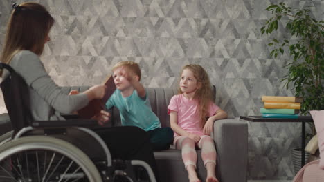 cute toddler gives book to mommy sitting near elder sister
