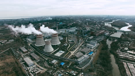 aerial view of industrial zone with factories expelling smoke around a green landscape