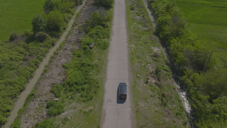 slow aerial tracking shot of a black suv heading toward a power plant