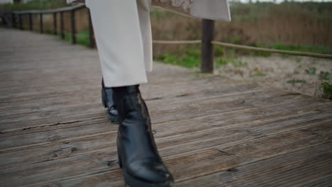 botas de otoño caminando camino de madera primer plano. piernas de viajero tranquilo paseando por la pasarela