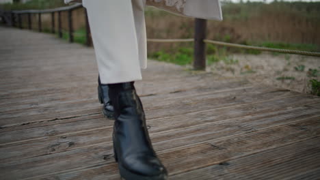 autumn boots walking wooden path closeup. calm traveler legs strolling walkway