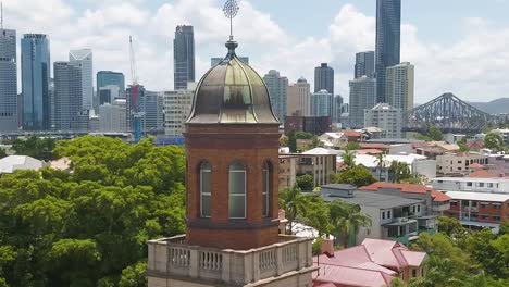 orbit around church tower with brisbane city skyline behind, aerial