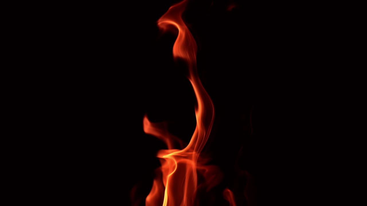 Dancing fire flame in the night. Mesmerizing tongues of blaze at black backdrop. Close up.