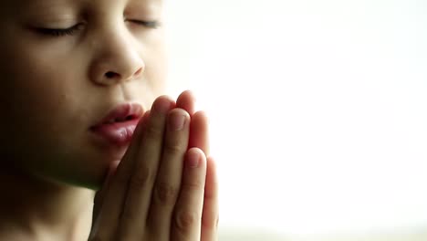 little-boy-praying-to-God-with-hands-together-on-white-background-with-people-stock-video