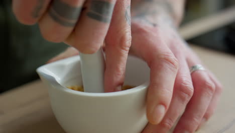 hands of chef grinding toasted sesame seeds with mortar and pestle