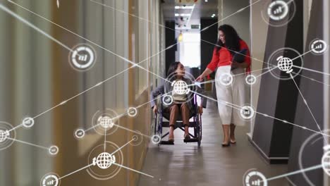 animation of connected graph and globe icons, diverse woman in wheelchair discussing with colleague