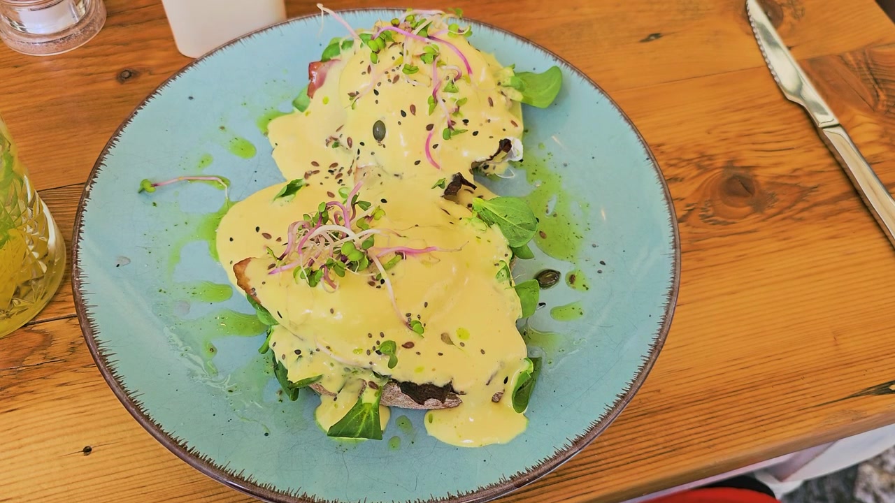 uova alla Benedict, brunch, salsa olandese, uova in camicia, toast, micro-ortaggi, caffè, ristorante, piatto blu, colazione, gourmet, primo piano, olio alle erbe, semi, fresco, tavolo rustico, video di cibo, pasto