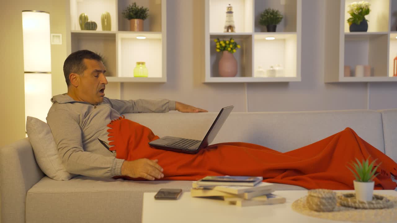 Man lying in bed using laptop confused.