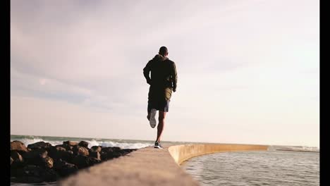 african american male jogger running on the beach 4k