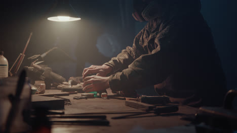 a bombmaker assembles a bomb in his workshop at night