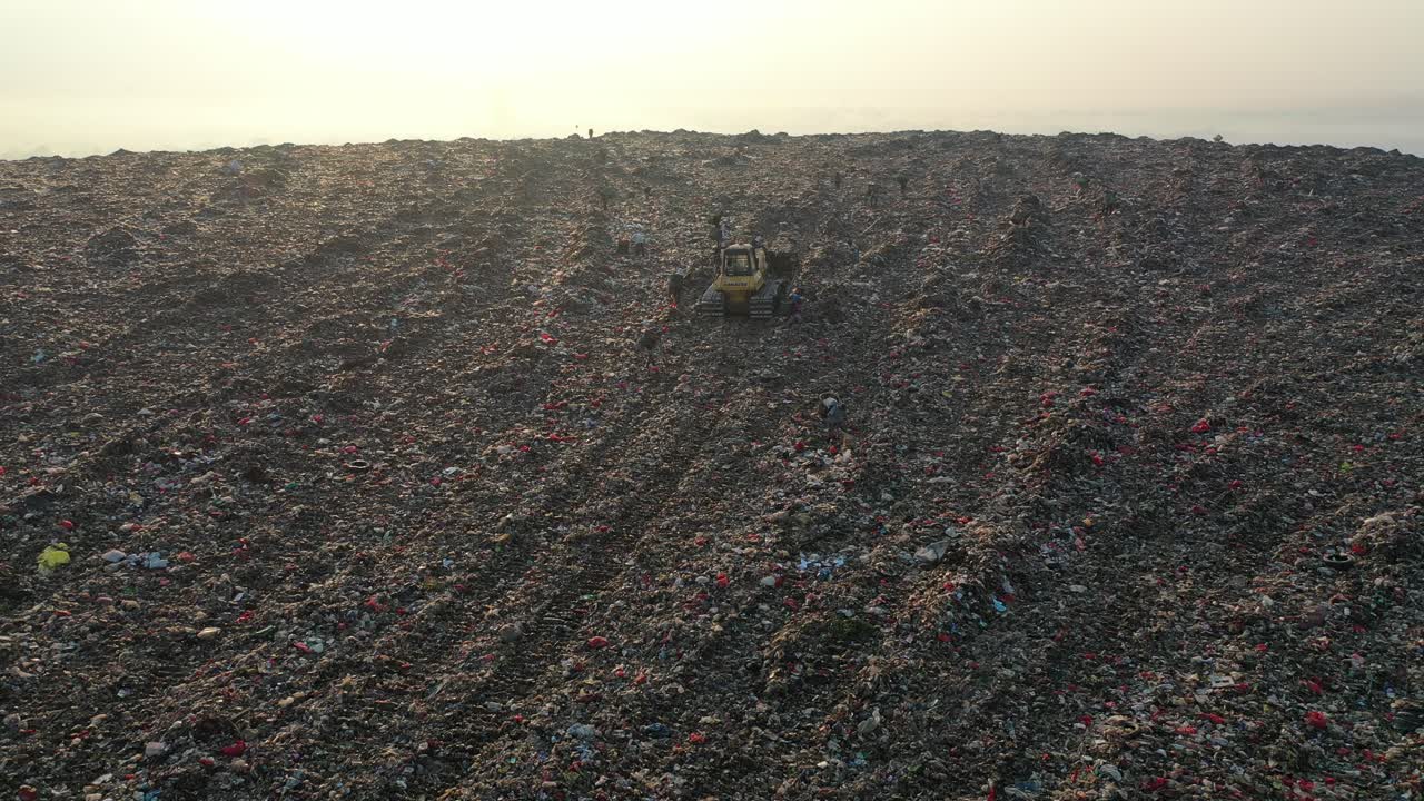 un vertedero masivo con trabajadores al amanecer.