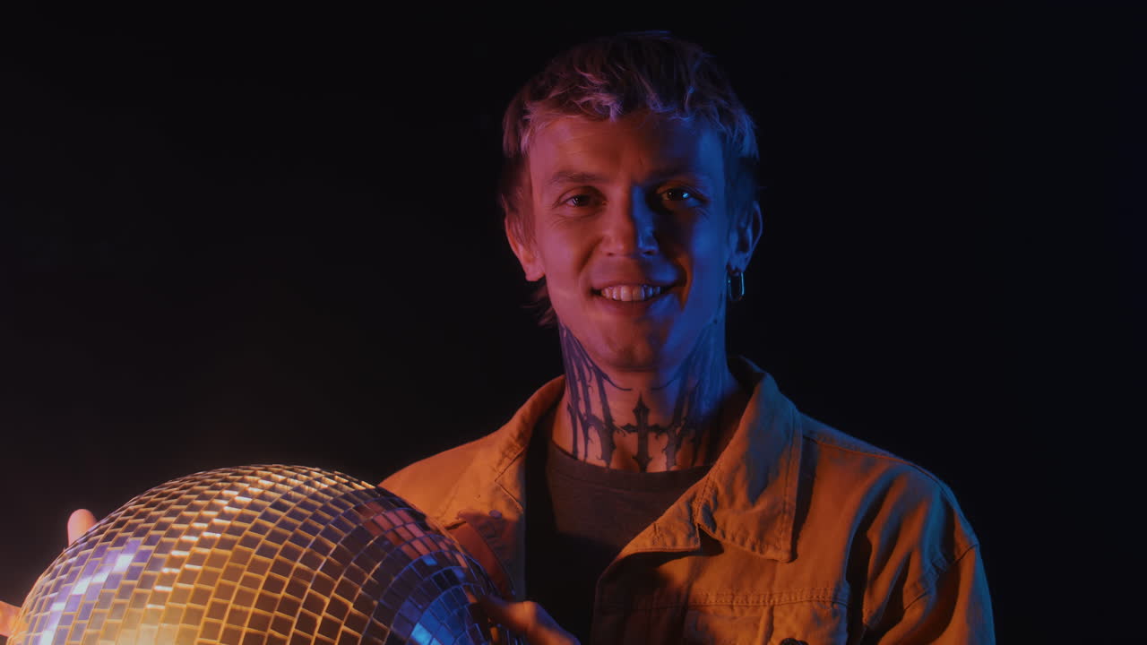 Caucasian Man Smiling at Camera with Disco Ball in Neon