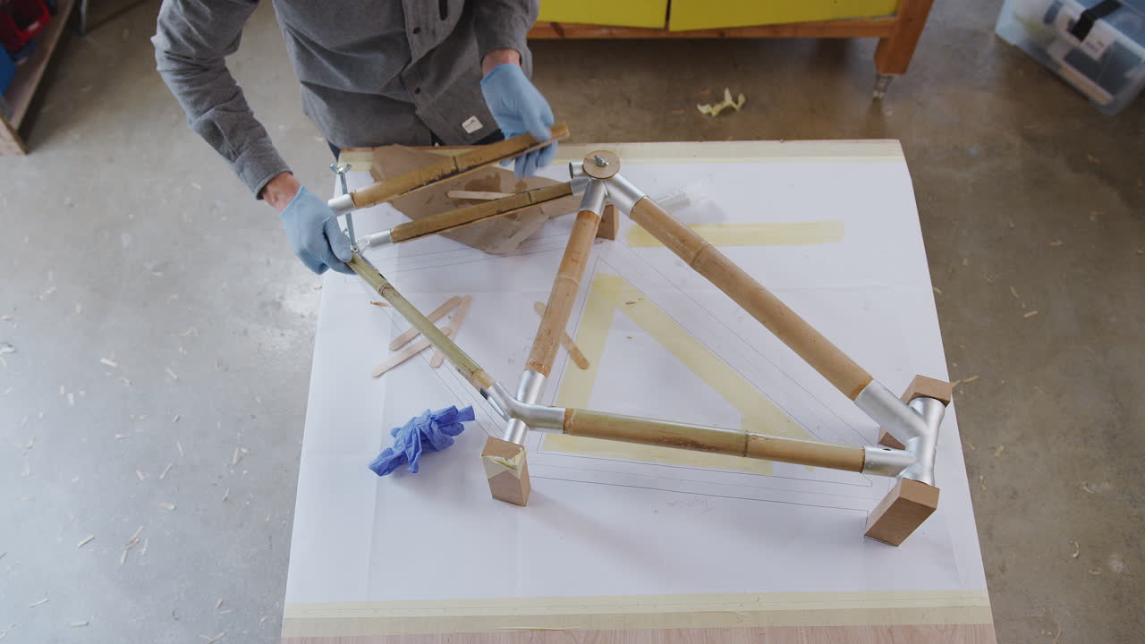 fotografía aérea de un artesano masculino en un taller de ensamblaje de un marco de bicicleta de bambú sostenible construido a mano
