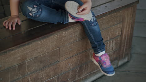 little child putting on shoes on her own