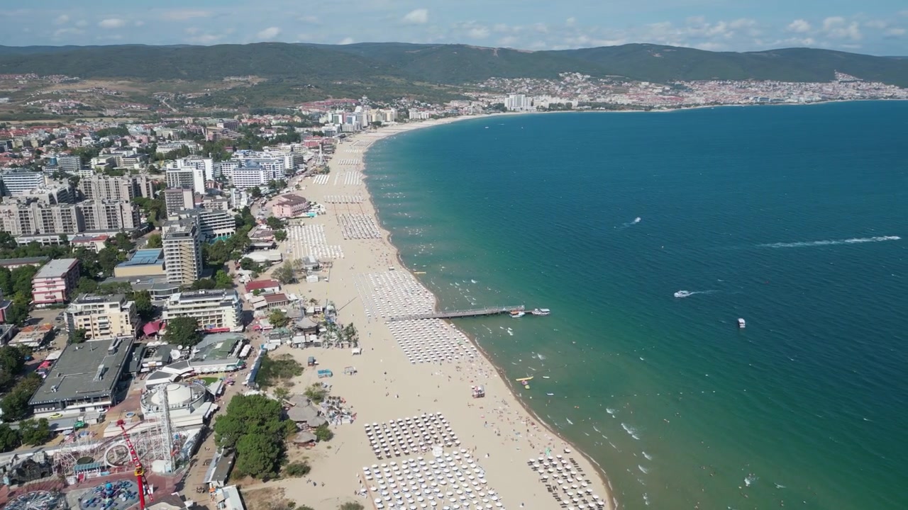 Bulgaristan'daki Sunny Beach'in geniş plajı boyunca ileri doğru uçan drone, uzun kıyı şeridini, Karadeniz'in turkuaz sularını ve yoğun tatil köyü gelişimini gözler önüne seriyor.