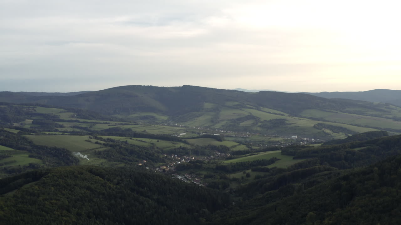 Ampia ripresa aerea lenta di verdi colline e un villaggio rurale nella Repubblica Ceca