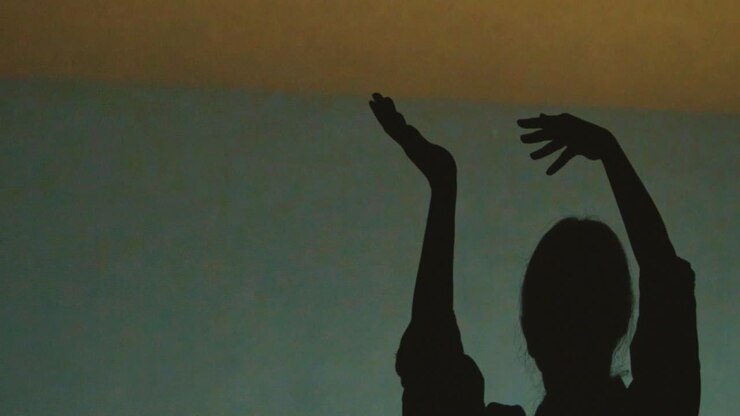 Silhouette Of Woman Visiting Immersive Art Exhibition With Projection Of Shapes And Patterns On Wall