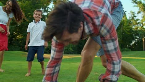 Parents-and-kids-playing-with-ball-in-meadow