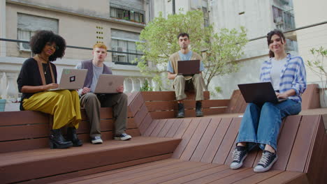 young business people with laptops sitting outdoors in the city and posing on camera