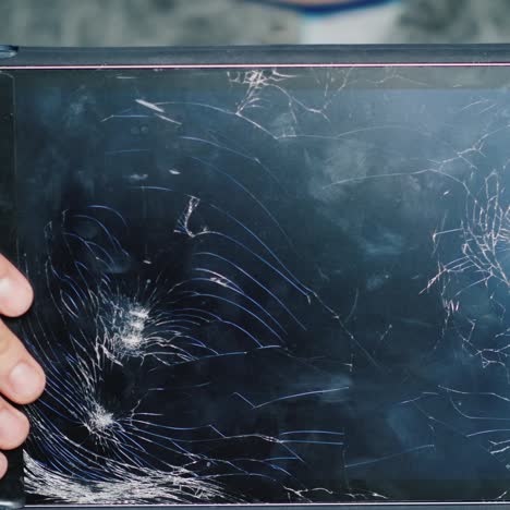 a man holds a tablet with a broken screen