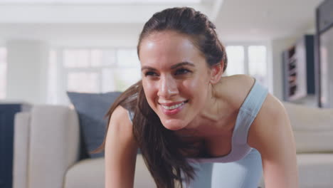 Woman-in-fitness-clothing-at-home-in-lounge-doing-stretches-and-exercising-on-mat---shot-in-slow-motion