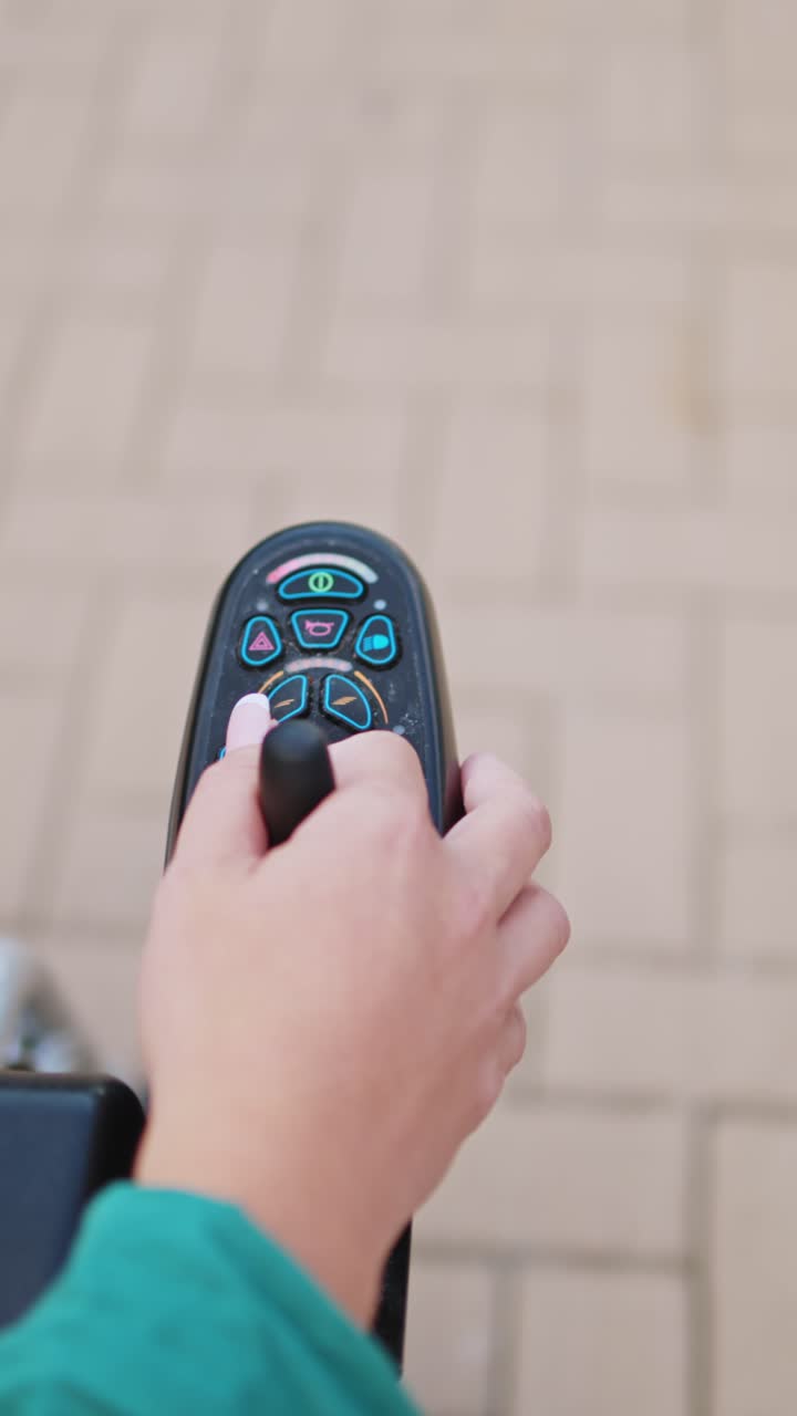Primo piano: mano che manovra il joystick di una sedia a rotelle elettrica
