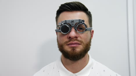 facial portrait of a man in trial frame. young handsome bearded man in medical glasses for testing eyes looking on camera. optical concept.