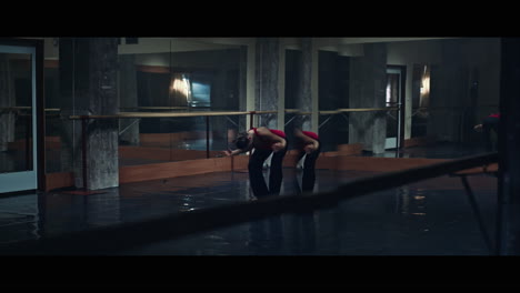 a young woman practices modern dancing and ballet in a moody room full of mirrors
