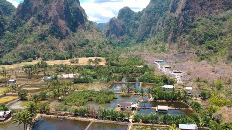 Aerial-of-beautiful-hidden-gem-Rammang-Rammang-Village-with-giant-limestone-cliffs,-authentic-cottages-and-huge-karst-mountains-in-Sulawesi,-Indonesia