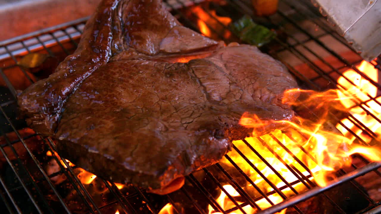 Bife grande sendo grelhado em churrasqueira flamejante