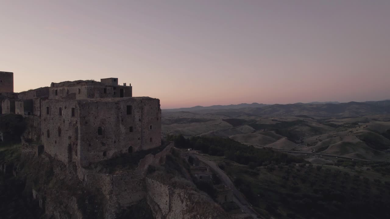 Drone flying in circulair motion around the ruins of Craco in the south of Italy in the very early morning sunrise in 4k