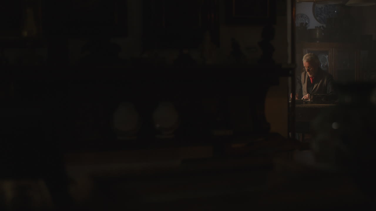 Old passionate man writes a letter in his office at night