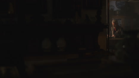 old passionate man writes a letter in his office at night