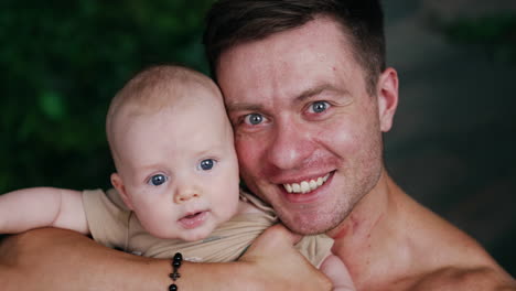 handsome caucasian man holding an infant child close to his face. portrait of a happy dad with his son. close up.