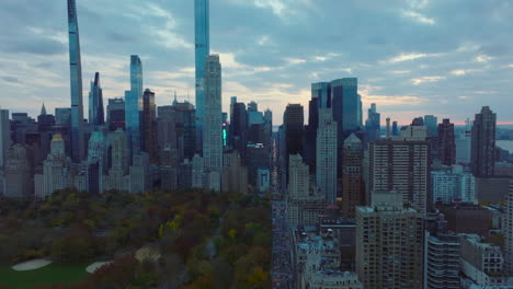 Los-Reenviadores-Vuelan-A-Lo-Largo-Del-Parque-Central-De-Otoño-Al-Atardecer.-Imágenes-Aéreas-De-Edificios-De-Gran-Altura-En-El-Parque-Circundante-Del-Centro.-Manhattan,-Ciudad-De-Nueva-York,-Estados-Unidos