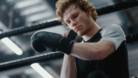 Serious-fighter-waiting-for-fight-at-gym.-Kickboxer-wearing-boxing-gloves