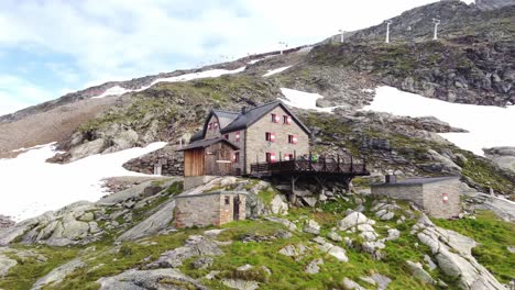 house surrounded by stones and a few snow fields with a rope way in the background in the alps in kaernten, austria