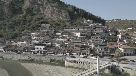 drone shot of the city of berat and its castle and fortress in albania, the city of a thousand windows on a sunny day in the valley with blue sky with white houses near the mountains log