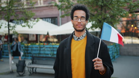man holding french flag in city street