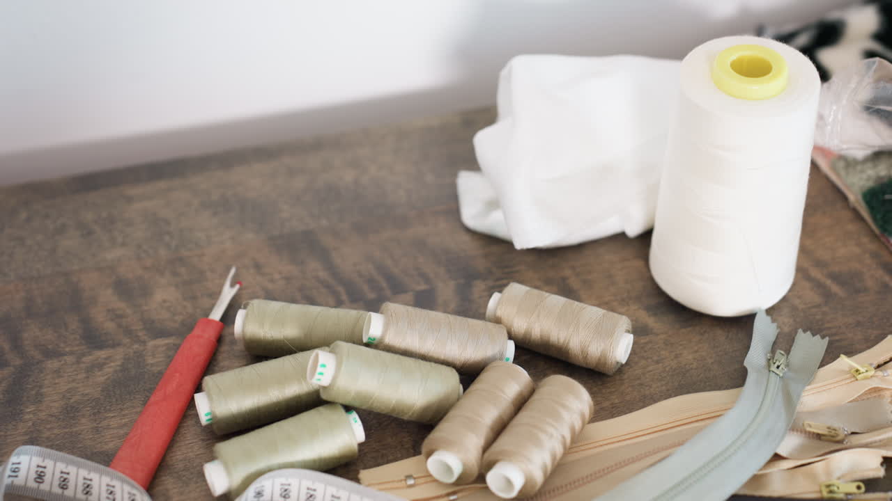 White, brown sewing thread, zippers, measuring tape on table, focusing on craft, highlighting creative environment, essential supplies for garment production, showcasing professional approach