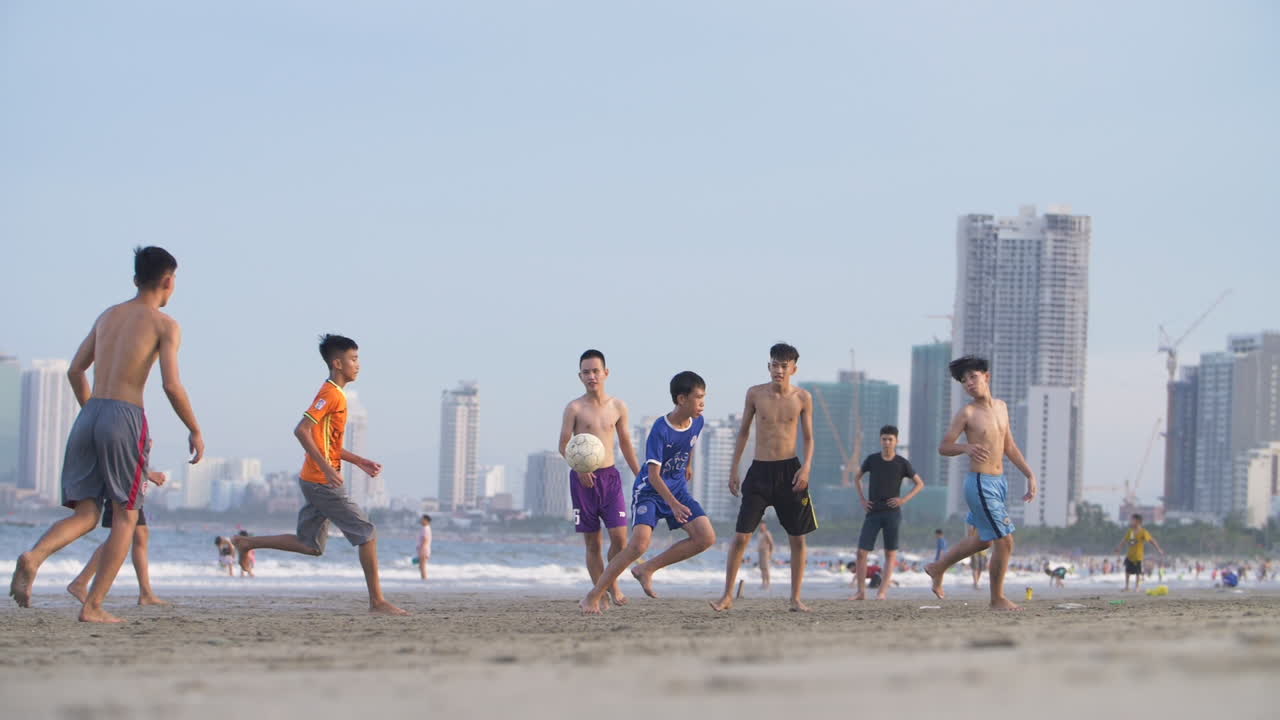 Boys playing soccer on sunny beach. Young, Active and Fit Activity. Football in Slow Motion