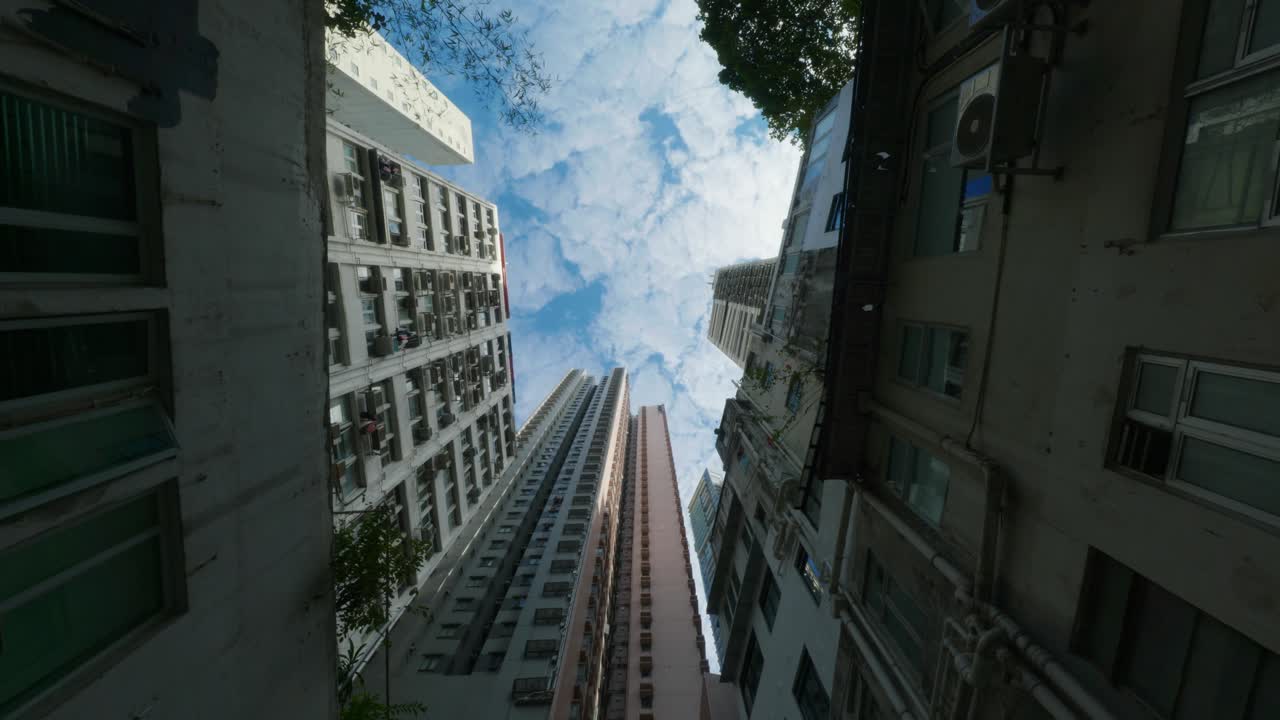 Vista panorâmica de edifícios de apartamentos e arranha-céus no centro de Hong Kong, China, em um dia ensolarado, mostrando a densidade da vida urbana e a arquitetura moderna.