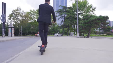 joven hombre de negocios montando un scooter eléctrico al aire libre.