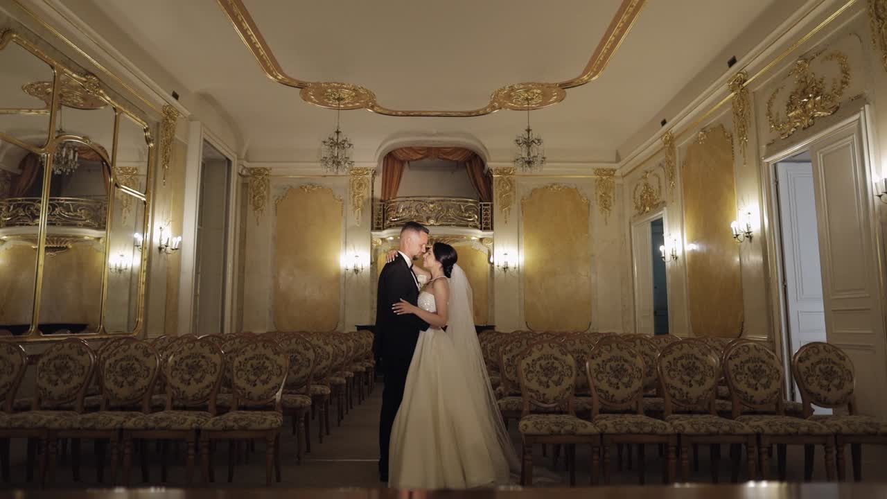 Retrato de recién casados, novio y novia caucásicos caminando, abrazándose en una habitación grande, pareja de recién casados.