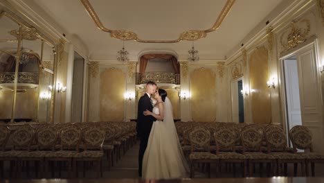 newlyweds portrait, caucasian groom bride walking, embracing, hugs in large room, wedding couple