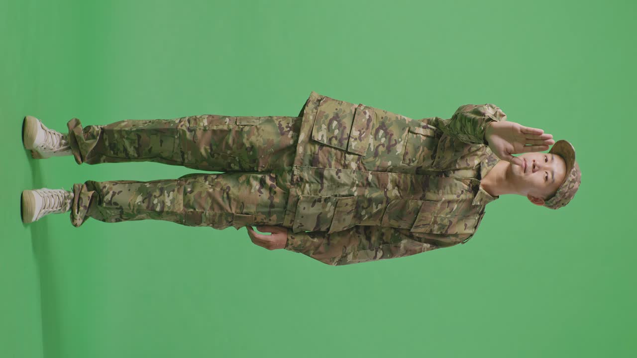 Full Body Of Asian Man Soldier Looking At Camera And Disapproving With No Hand Sign While Standing In The Green Screen Background Studio