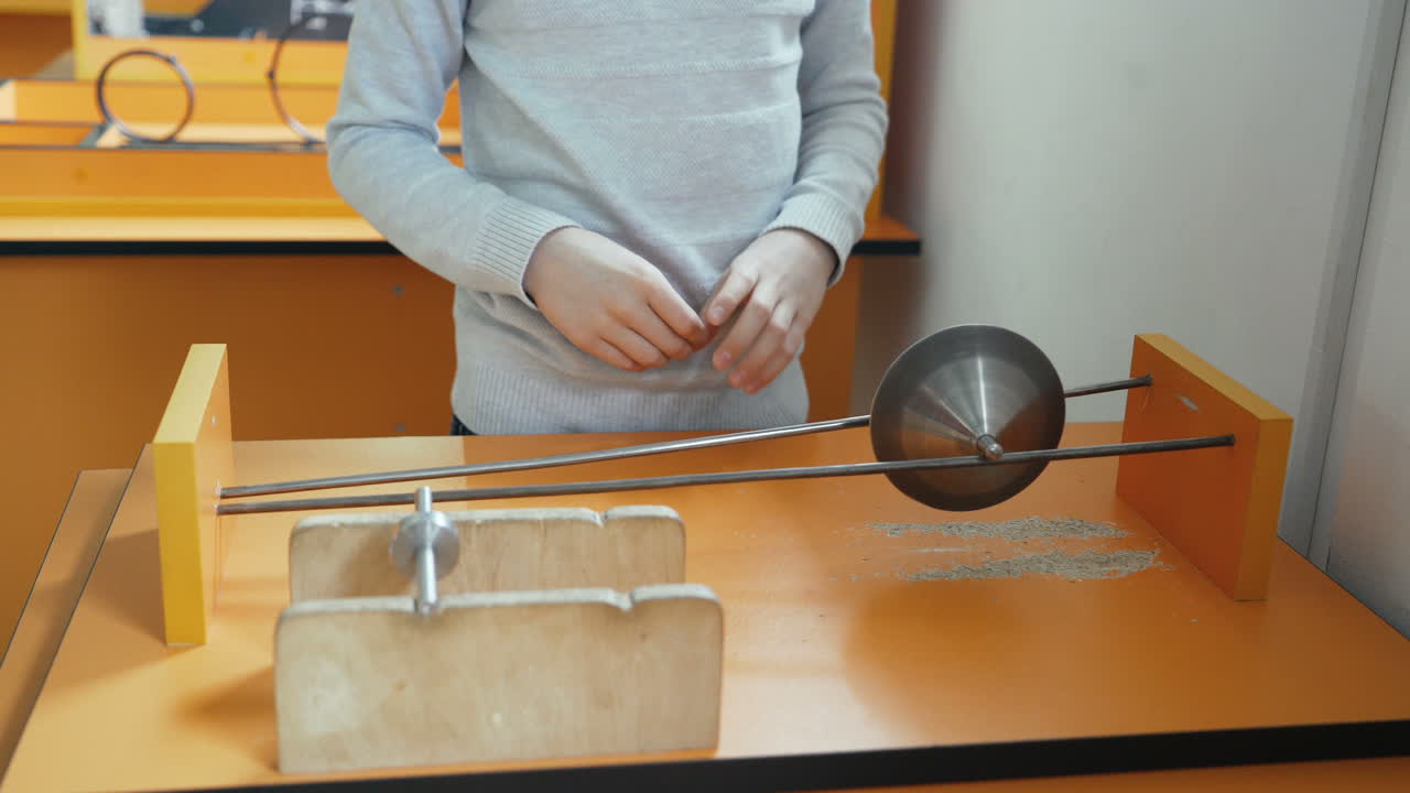 Boy looks like a cone falls down under the action of the center of mass. Concept of physics. Museum of Science